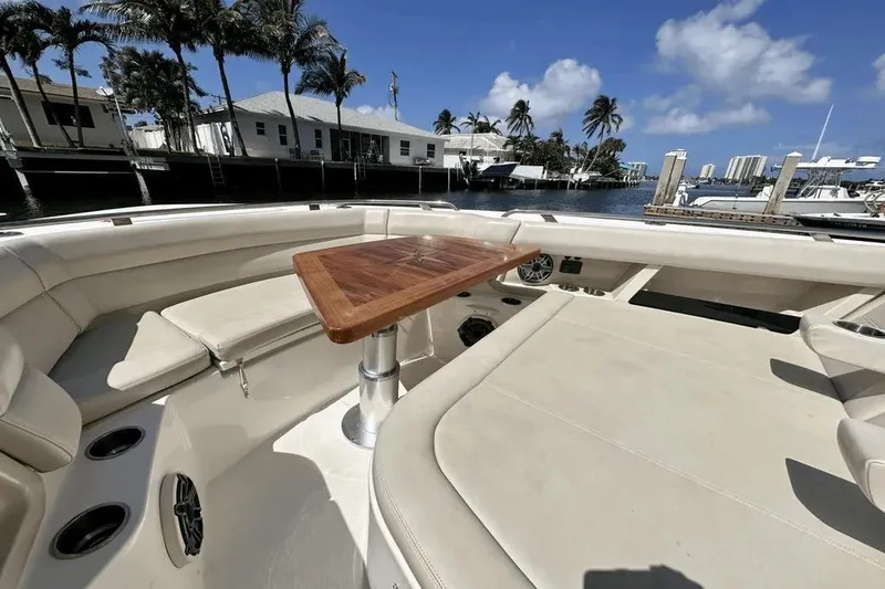 Slide: The Image of 2019 Boston Whaler 350 Realm boat interior with seating and wooden table, docked by waterfront homes. - 19