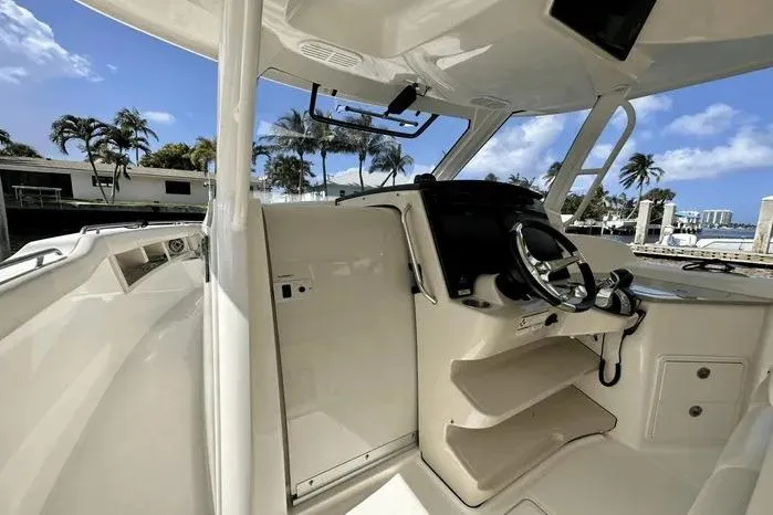 Slide: The Image of 2019 Boston Whaler 350 Realm helm with steering wheel, tropical marina backdrop. - 14