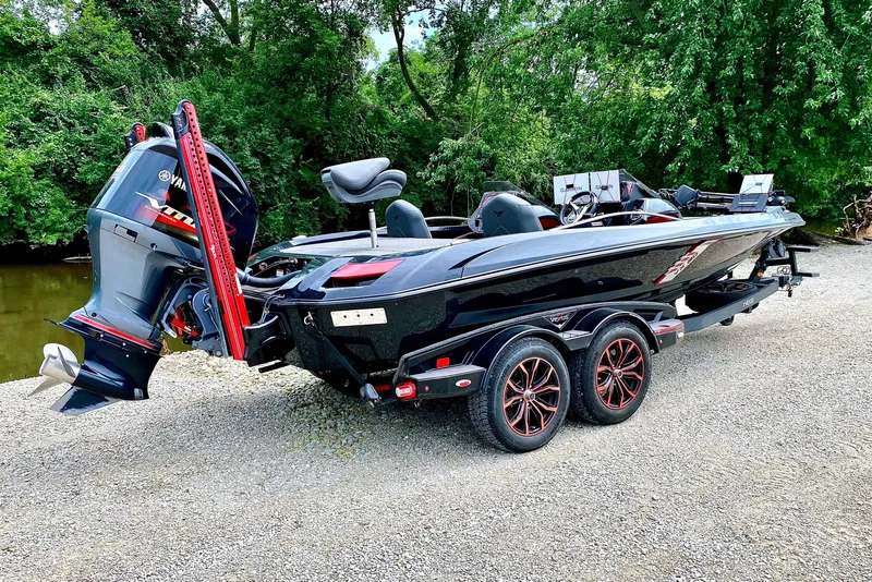 Slide: The Image of A black 2020 Vexus VX20 boat on a trailer, surrounded by trees. - 2