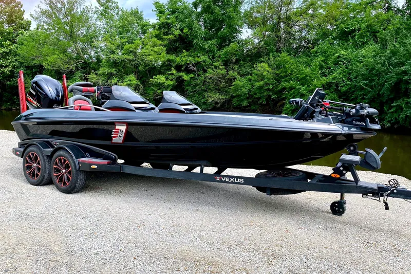 The Image of A black 2020 Vexus VX20 boat on a trailer, surrounded by trees. - 1