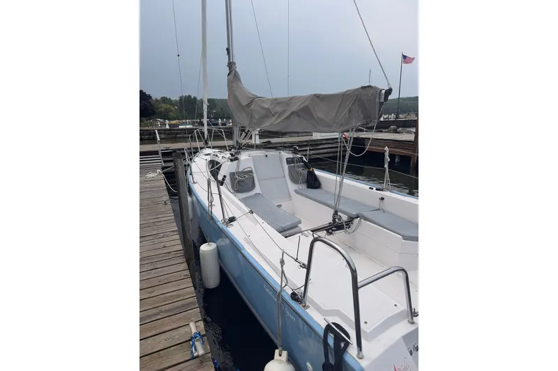 Slide: The Image of 2015 Catalina 275 Sport sailboat docked at a marina, featuring a sleek design and covered sail. - 2