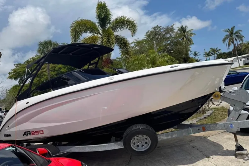 Slide: The Image of 2024 Yamaha Boats AR250 on trailer, surrounded by palm trees and blue sky. - 2