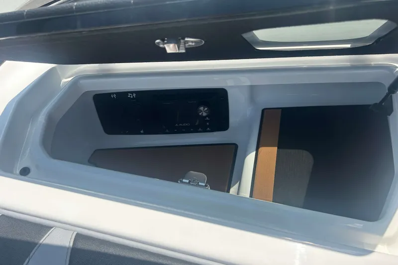 Slide: The Image of Storage compartment in 2022 Nautique Super Air Nautique G21 boat with audio controls. - 17