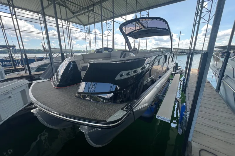 The Image of 2023 Harris Crowne SL 250 pontoon boat docked under a canopy on a sunny day. - 0