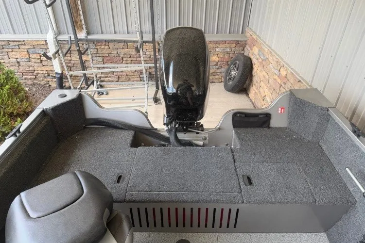 Slide: The Image of 2026 Crestliner 1650 Kodiak SC boat interior with motor, gray seating, and storage compartments. - 12