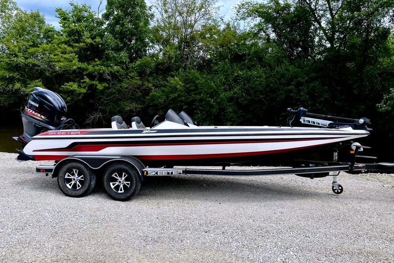 Slide: The Image of 2017 Skeeter ZX250 bass boat with sleek design, on a trailer, surrounded by trees. - 2