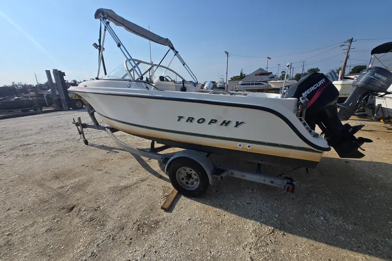 Slide: The Image of Bayliner 1700 Trophy Dual Console 2001 boat on trailer, outdoor setting, sunny day. - 1