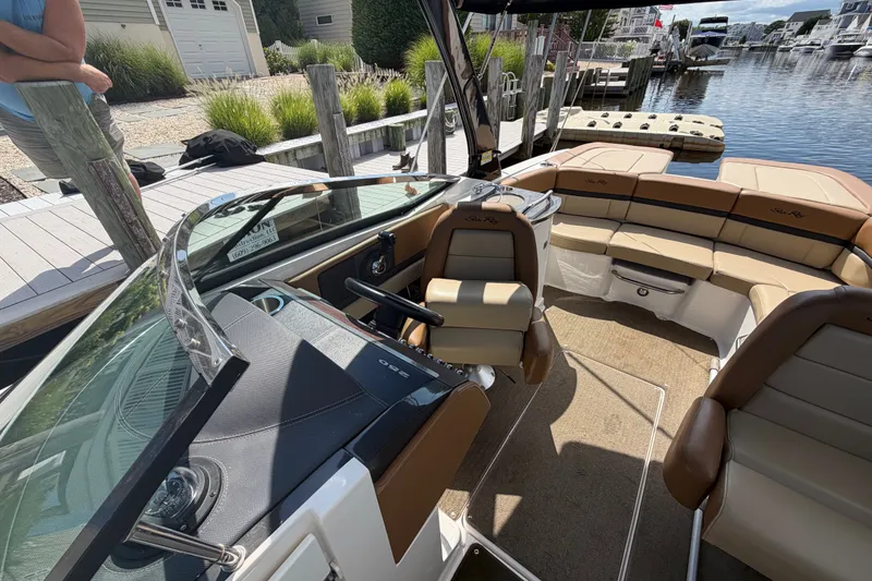 Slide: The Image of 2014 Sea Ray SLX 250 boat interior with tan seating, docked by a waterfront. - 12
