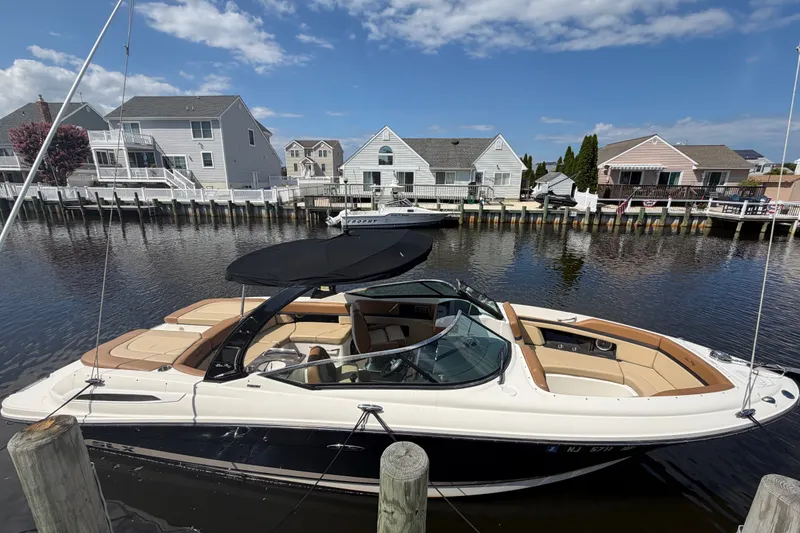 Slide: The Image of 2014 Sea Ray SLX 250 boat docked by waterfront homes under a clear blue sky. - 2