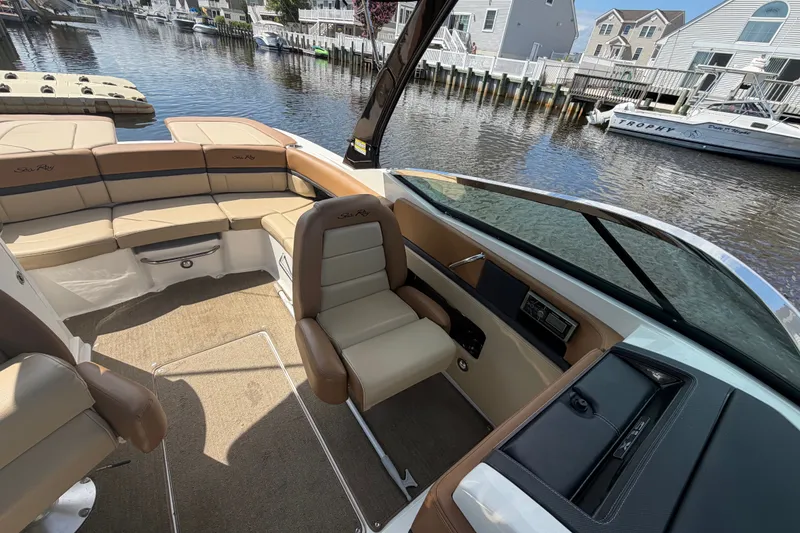 Slide: The Image of 2014 Sea Ray SLX 250 boat interior with beige seating, docked by waterfront homes. - 13