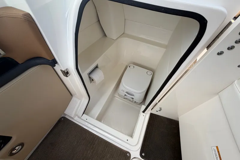 Slide: The Image of 2014 Sea Ray SLX 250 boat interior with compact marine toilet and storage space. - 22