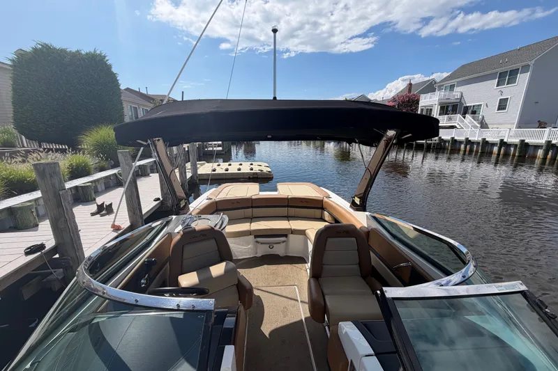 Slide: The Image of 2014 Sea Ray SLX 250 boat docked by a canal, featuring a spacious seating area. - 11