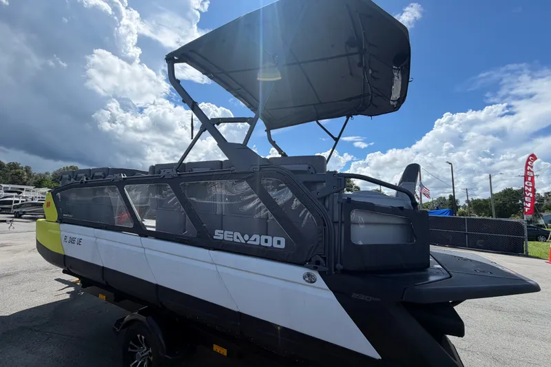 Slide: The Image of 2023 Sea-Doo Switch Cruise 21 pontoon boat with canopy, parked outdoors under a cloudy sky. - 7