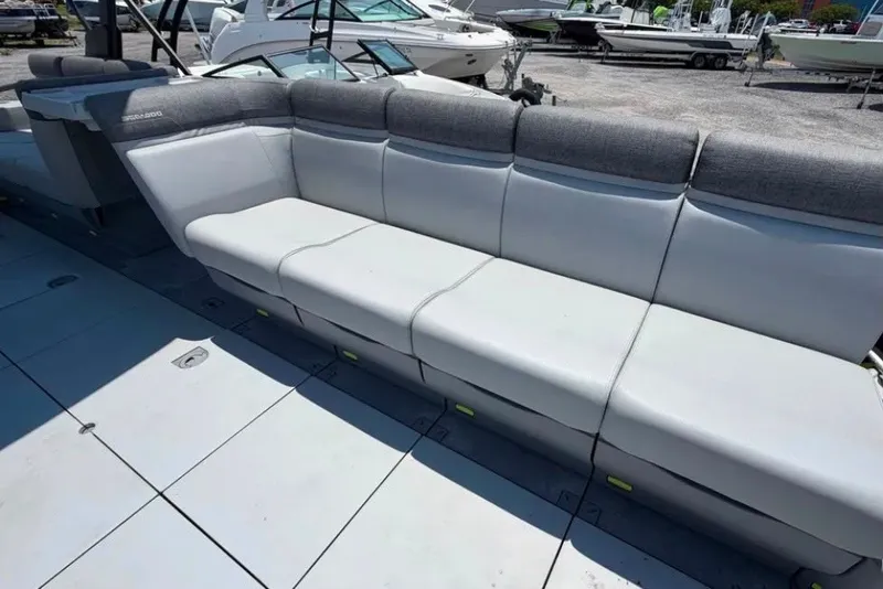 Slide: The Image of 2023 Sea-Doo Switch Cruise 21 boat seating area with gray upholstery in a marina setting. - 10