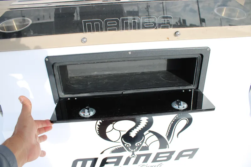 Slide: The Image of 2026 Mamba 24 Cat Elite boat compartment with logo and hand opening hatch. - 15
