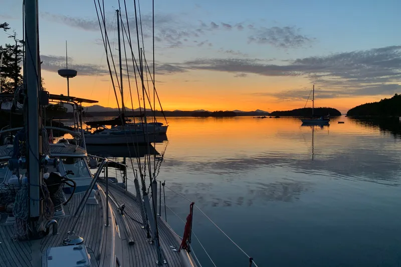 Slide: The Image of Sailboats on tranquil water at sunset, featuring a 1997 Hallberg-Rassy 42F. - 98