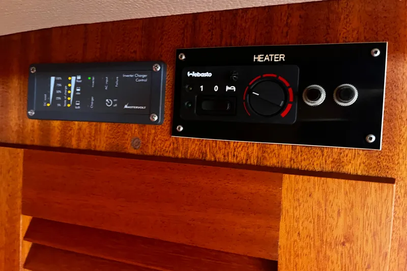 Slide: The Image of Control panels on a 1997 Hallberg-Rassy 42F yacht, featuring heater and inverter charger controls. - 24