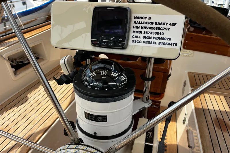 Slide: The Image of Steering wheel and compass of 1997 Hallberg-Rassy 42F sailboat, featuring navigation equipment. - 56
