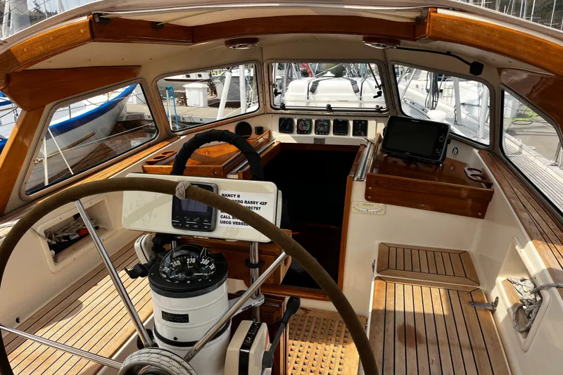 Slide: The Image of Interior view of a 1997 Hallberg-Rassy 42F sailboat cockpit with wooden accents and navigation equipment. - 55
