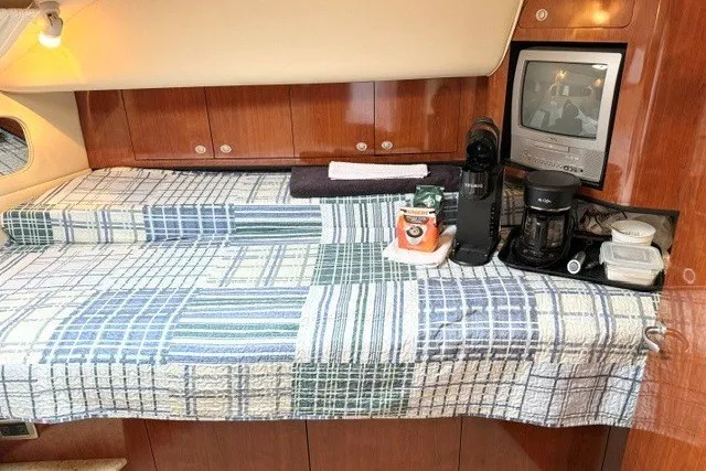 Slide: The Image of 2004 Sea Ray 390 Motor Yacht interior with bed, TV, and coffee maker setup. - 30