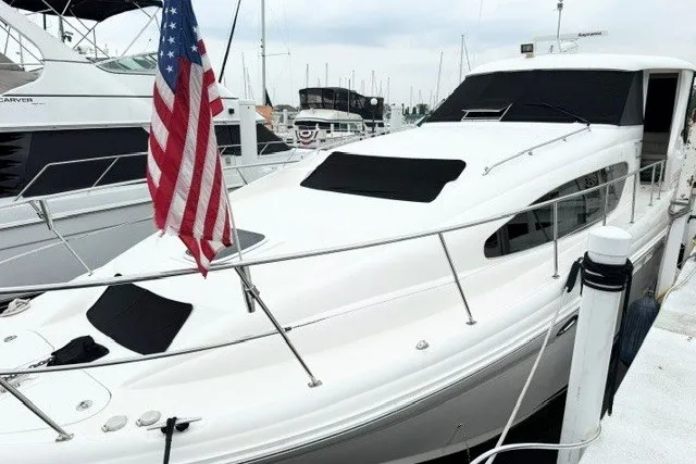 Slide: The Image of 2004 Sea Ray 390 Motor Yacht docked with American flag, sleek design, and covered windows. - 3