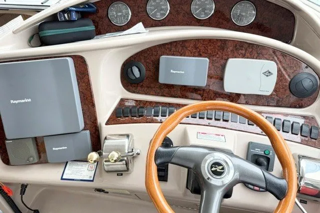Slide: The Image of 2004 Sea Ray 390 Motor Yacht helm with Raymarine navigation equipment and wood-accented steering wheel. - 38