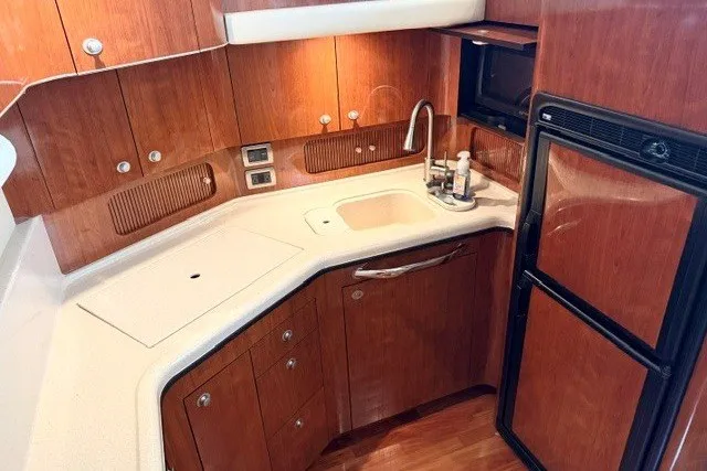 Slide: The Image of 2004 Sea Ray 390 Motor Yacht kitchen with wood cabinetry, sink, and appliances. - 28