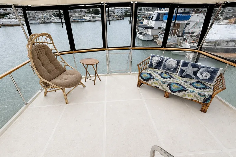 Slide: The Image of 1988 Angel 45 AFT CABIN MV interior with wicker seating, nautical-themed cushions, and marina view. - 6