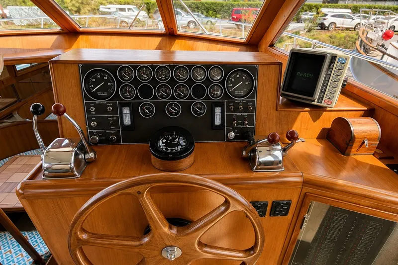 Slide: The Image of 1988 Angel 45 AFT CABIN MV boat helm with gauges, wooden wheel, and control levers. - 9