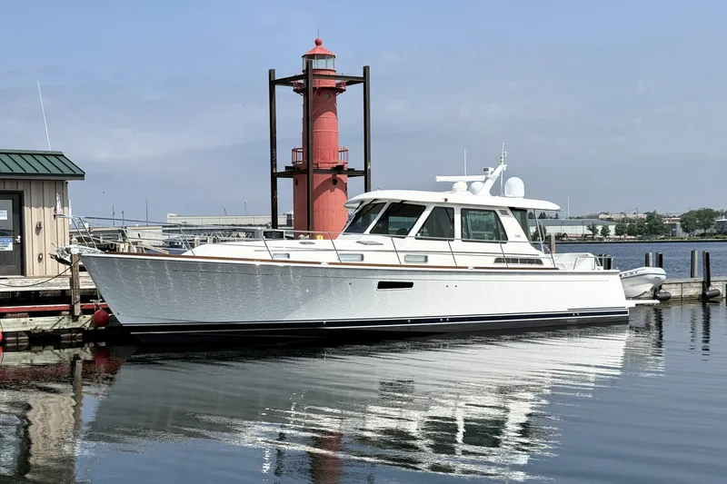 The Image of 2022 Sabre 48 Salon Express yacht docked near a red lighthouse. - 0