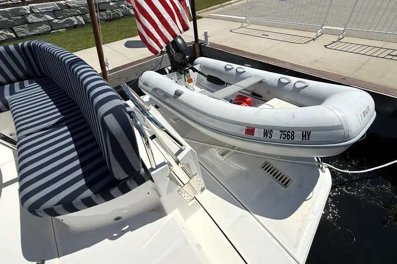Slide: The Image of 2022 Sabre 48 Salon Express with striped seating and inflatable dinghy at dock. - 7