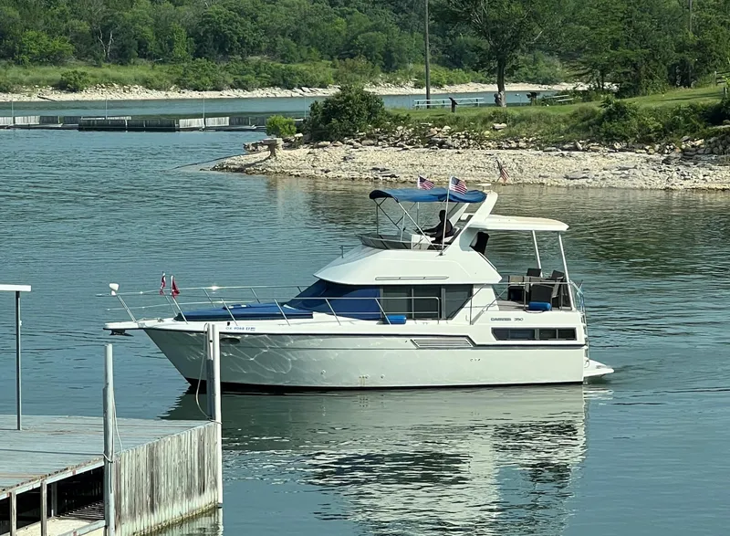 The Image of 1994 Carver 350 Aft Cabin yacht on a serene lake with lush green surroundings. - 0