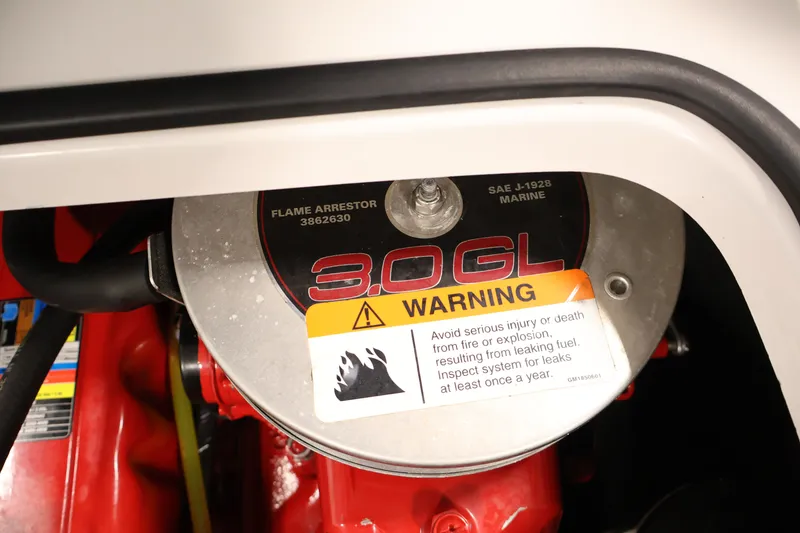 Slide: The Image of Engine compartment of 2009 Four Winns H180 boat, featuring 3.0 GL flame arrestor and warning label. - 34