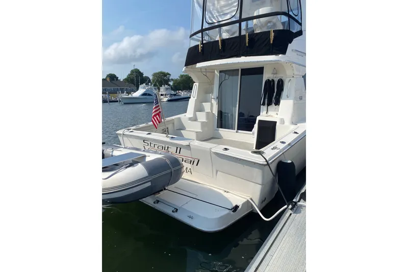 Slide: The Image of 2001 Silverton 42 Convertible yacht docked with inflatable boat and American flag. - 5