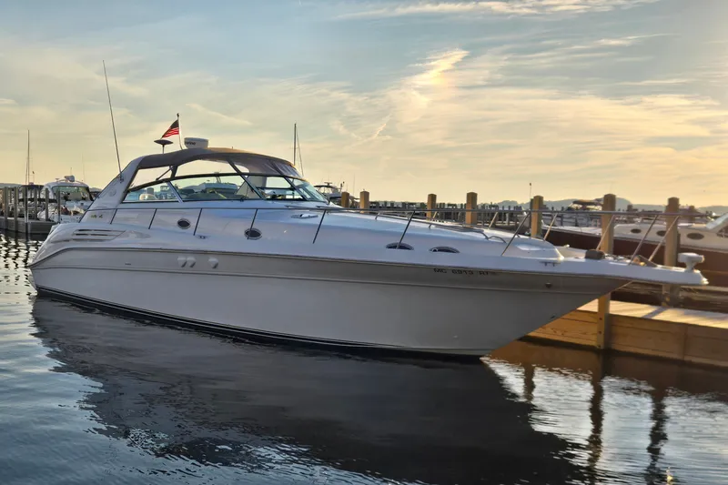 The Image of 1999 Sea Ray 450 Sundancer yacht docked at marina during sunset. - 1