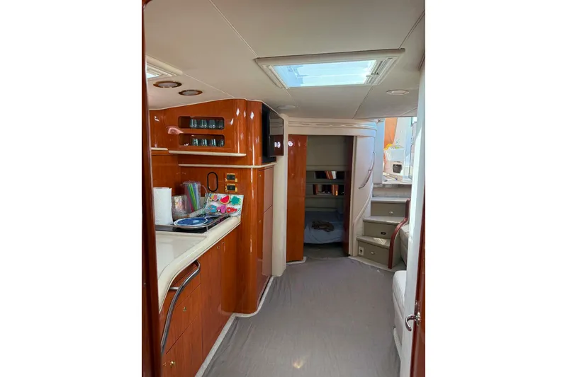 Slide: The Image of 1999 Sea Ray 450 Sundancer interior with kitchenette and stairs, featuring wood cabinetry. - 21