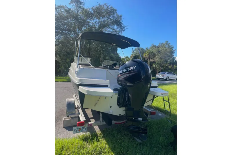 Slide: The Image of 2017 Bayliner 190 Deck Boat with Mercury outboard engine on trailer. - 2