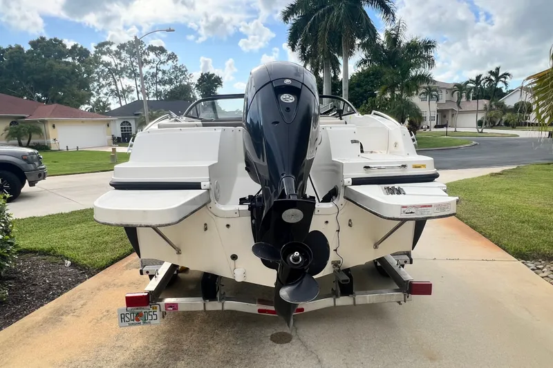 Slide: The Image of 2017 Bayliner 190 Deck Boat on trailer, parked in suburban driveway with palm trees. - 3