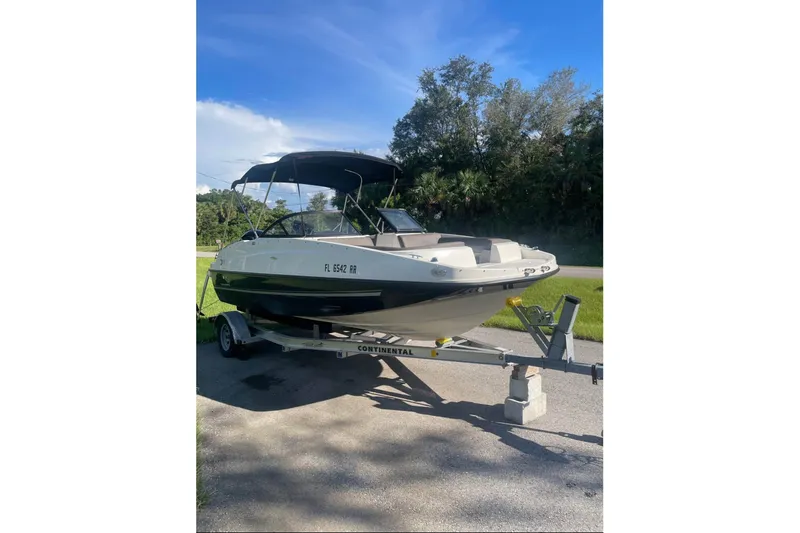 The Image of 2017 Bayliner 190 Deck Boat on trailer, parked outdoors under clear blue sky. - 0