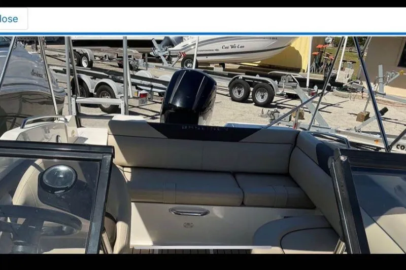 Slide: The Image of 2017 Bayliner 190 Deck Boat interior with seating and motor, parked on a trailer. - 4
