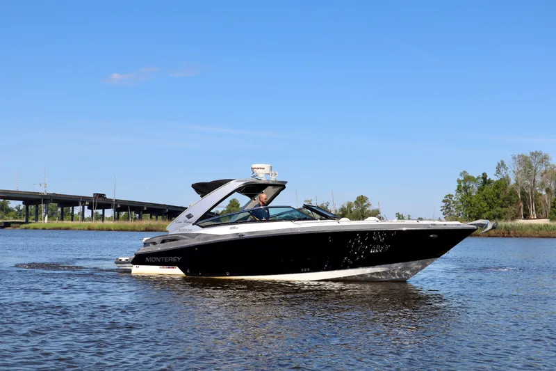 Slide: The Image of 2014 Monterey 328SS Super Sport boat cruising on a calm river under a clear blue sky. - 18
