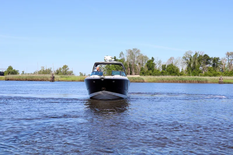 Slide: The Image of 2014 Monterey 328SS Super Sport boat cruising on a calm river under a clear blue sky. - 15