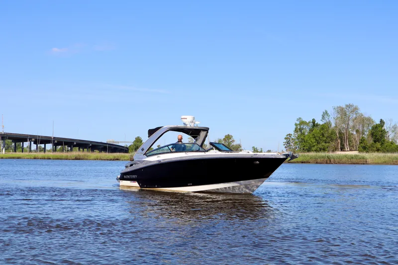 Slide: The Image of 2014 Monterey 328SS Super Sport boat cruising on a calm river under a clear blue sky. - 17