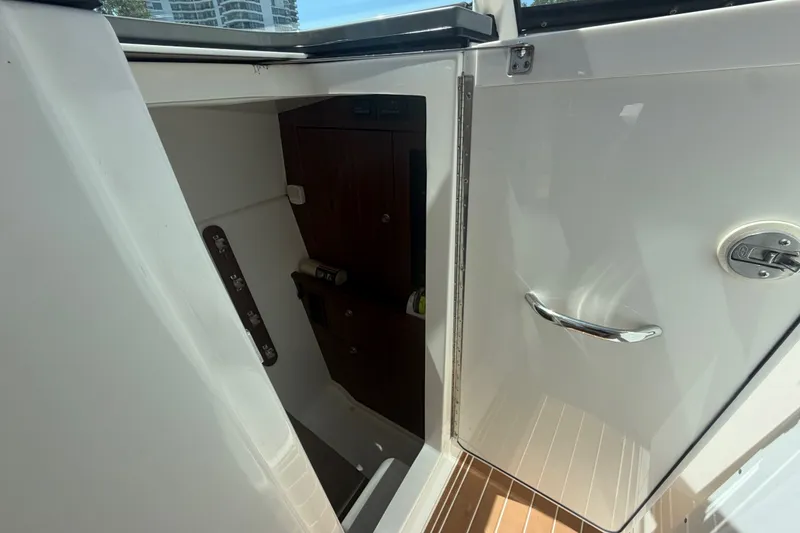 Slide: The Image of 2016 Pursuit DC 325 Dual Console interior storage compartment with wooden accents and chrome handle. - 44