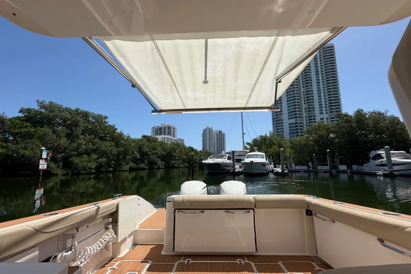 Slide: The Image of 2016 Pursuit DC 325 Dual Console boat docked with city skyline and trees. - 13
