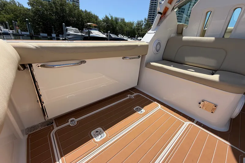 Slide: The Image of 2016 Pursuit DC 325 Dual Console interior with tan seating and teak-style flooring. - 19