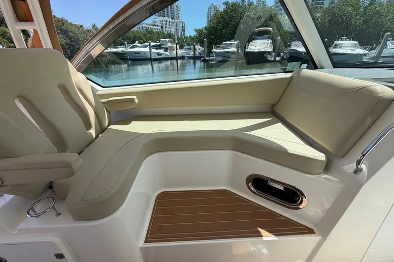 Slide: The Image of Interior of 2016 Pursuit DC 325 Dual Console boat with beige seating and marina view. - 42