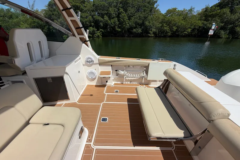 Slide: The Image of 2016 Pursuit DC 325 Dual Console boat interior with beige seating and wood-style flooring. - 14