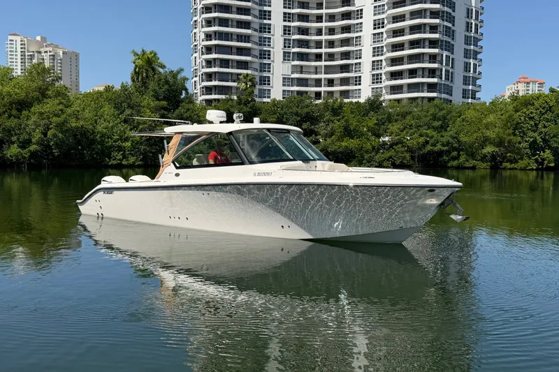 Slide: The Image of 2016 Pursuit DC 325 Dual Console boat on calm water with modern buildings in the background. - 5