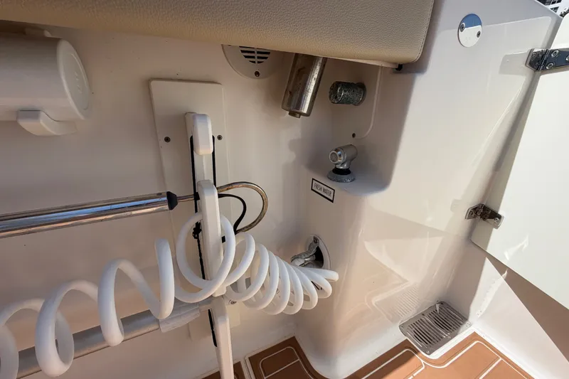 Slide: The Image of 2016 Pursuit DC 325 Dual Console boat interior with fresh water hose and storage compartment. - 54